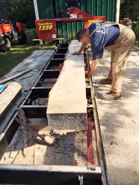 Robert adjusts his TimberKing sawmill to saw boards he'll turn into molding, casing, flooring or other hardwood products. Both he and Amy run this mill.